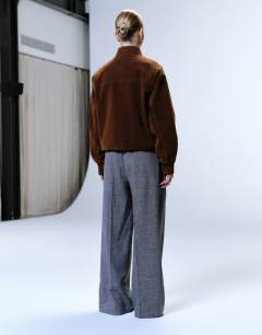 Model wearing Raw hem low slung double pleated tailored trouser in dark charcoal