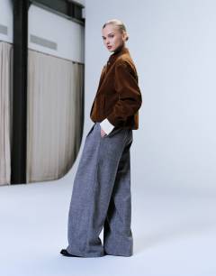 Model wearing Raw hem low slung double pleated tailored trouser in dark charcoal