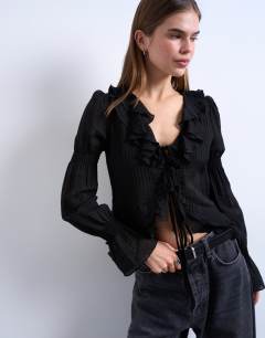 Model wearing Ruffle tie front long sleeve top in black