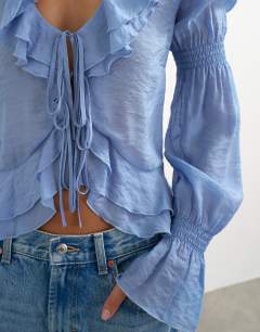 Model wearing Ruffle tie front long sleeve top in pale blue