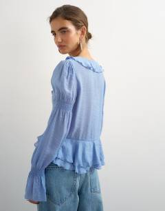 Model wearing Ruffle tie front long sleeve top in pale blue