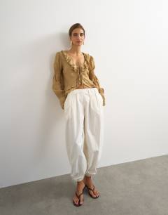 Model wearing Ruffle tie front long sleeve top in tan