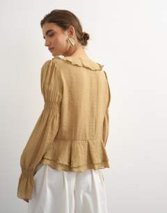 Model wearing Ruffle tie front long sleeve top in tan