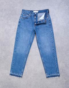 Model wearing Runway mid rise straight cropped jean with let down hem detail in mid blue