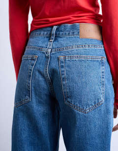 Model wearing Runway mid rise straight cropped jean with let down hem detail in vintage blue