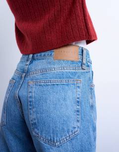 Model wearing Runway mid rise straight jeans in mid blue