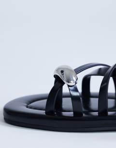 Model wearing Sabrina metal toe flat sandal in black