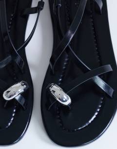 Model wearing Sabrina metal toe flat sandal in black