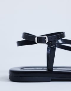 Model wearing Sabrina metal toe flat sandal in black