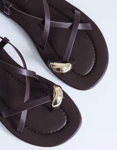 Model wearing Sabrina metal toe flat sandal in chocolate