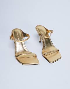 Model wearing Sally 2 part metal heeled sandal in gold