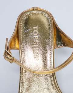 Model wearing Sally 2 part metal heeled sandal in gold