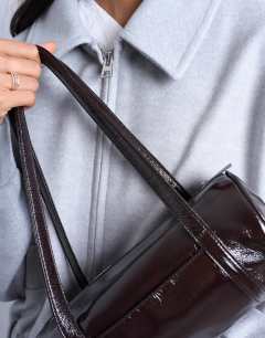 Model wearing Salma bowler bag in chocolate patent