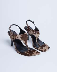 Model wearing Sandy hair on real leather toe thong heeled sandal in brown cow print