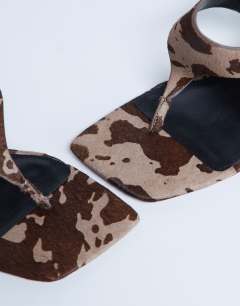 Model wearing Sandy hair on real leather toe thong heeled sandal in brown cow print
