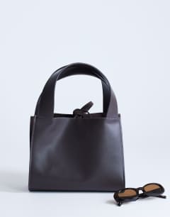 Model wearing Sandy small real suede and leather grab bag with tie fastening in chocolate