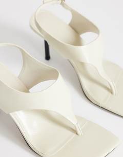Model wearing Sandy toe thong heeled sandal in off white