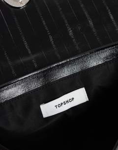 Model wearing Santiago small suedette shoulder bag with silver hardware in black