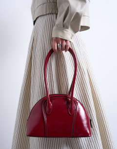 Model wearing Saoirse patent shoulder bag in burgundy