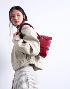 Model wearing Saoirse patent shoulder bag in burgundy