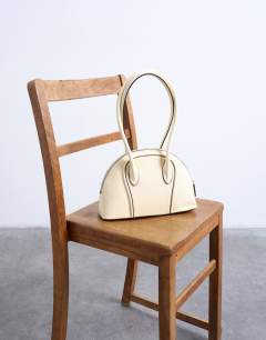Model wearing Saoirse patent shoulder bag in buttermilk