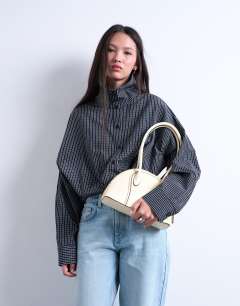 Model wearing Saoirse patent shoulder bag in buttermilk