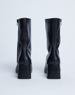 Model wearing Sara Premium leather square toe flared heel boot in black