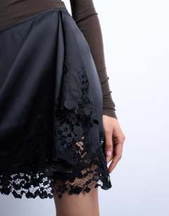 Model wearing Satin asymmetric mini skirt with lace trim in black