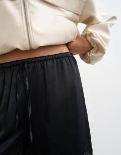 Model wearing Satin feel lace insert bermuda short in black