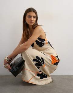 Model wearing Satin low scoop flood length slip dress in black and orange bold floral