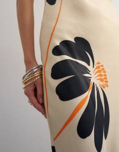 Model wearing Satin low scoop flood length slip dress in black and orange bold floral