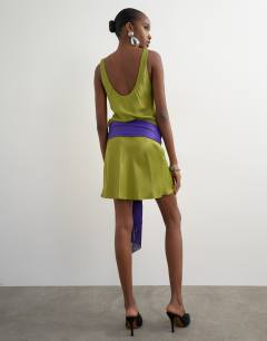 Model wearing Satin scoop neck dropped waist mini dress with fringed tie in green and purple