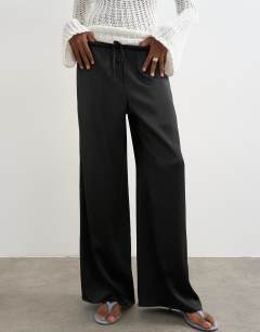 Model wearing Satin tie waist wide leg trouser in black