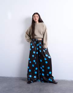 Model wearing Satin wide leg trousers in blue and brown polka dot