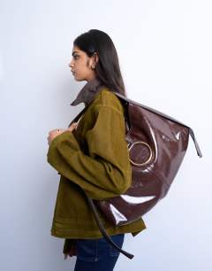 Model wearing Saturn hardware shoulder bag in chocolate