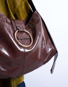 Model wearing Saturn hardware shoulder bag in chocolate