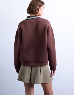 Model wearing Scuba-style fabric knit collar piped polo sweat in chocolate brown