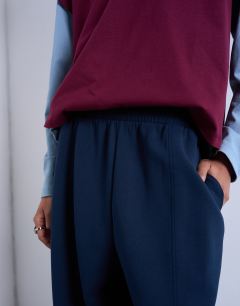 Model wearing Scuba-style fabric pintuck barrel leg jogger in navy