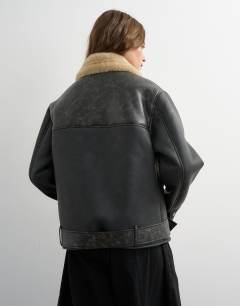 Model wearing Shearling belted biker jacket in black and cream