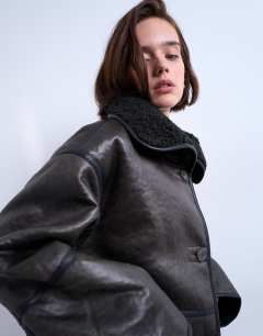 Model wearing Shearling oversized patch pocket mid length funnel neck car coat in black