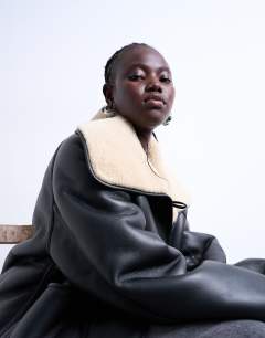 Model wearing Shearling oversized reversible coat with button loop in black and cream