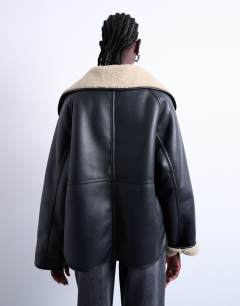 Model wearing Shearling oversized reversible coat with button loop in black and cream