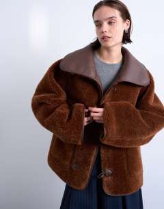 Model wearing Shearling oversized reversible coat with button loop in chocolate