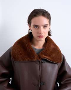 Model wearing Shearling oversized reversible coat with button loop in chocolate