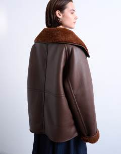 Model wearing Shearling oversized reversible coat with button loop in chocolate