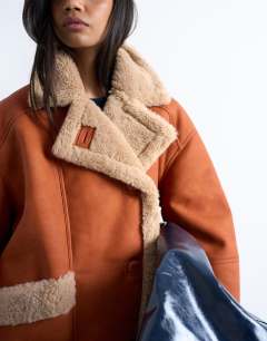 Model wearing Shearling  super oversized car coat in tan and cream