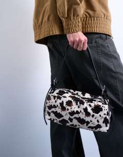 Model wearing Siris medium buckle shoulder bag in cow print