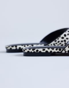 Model wearing Sisi toe thong flat sandal in dalmatian print hair on real leather
