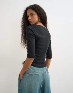 Model wearing Slash neck curve hem top in black