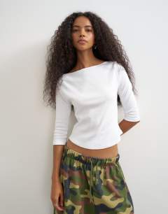 Model wearing Slash neck curve hem top in white
